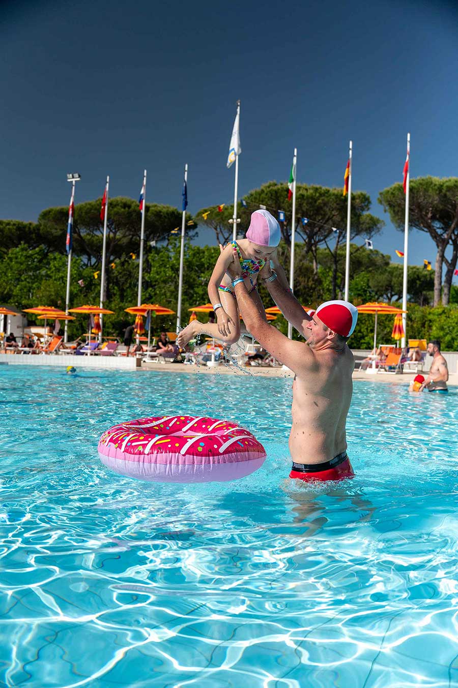 Papà e bambina che giocano in piscina con un gonfiabile