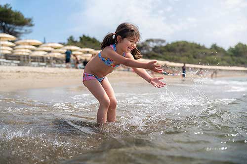 Bambina che gioca in acqua davanti allo stabilimento balneare Pappabeach
