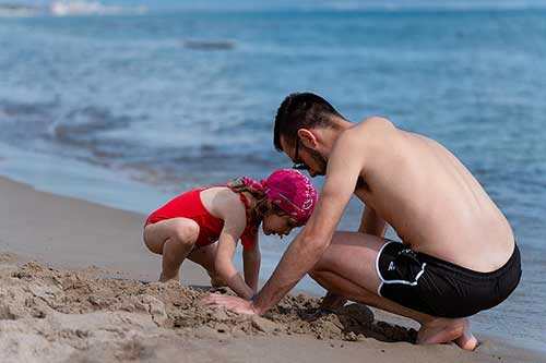 Papà con bambina che giocano sulla battigia
